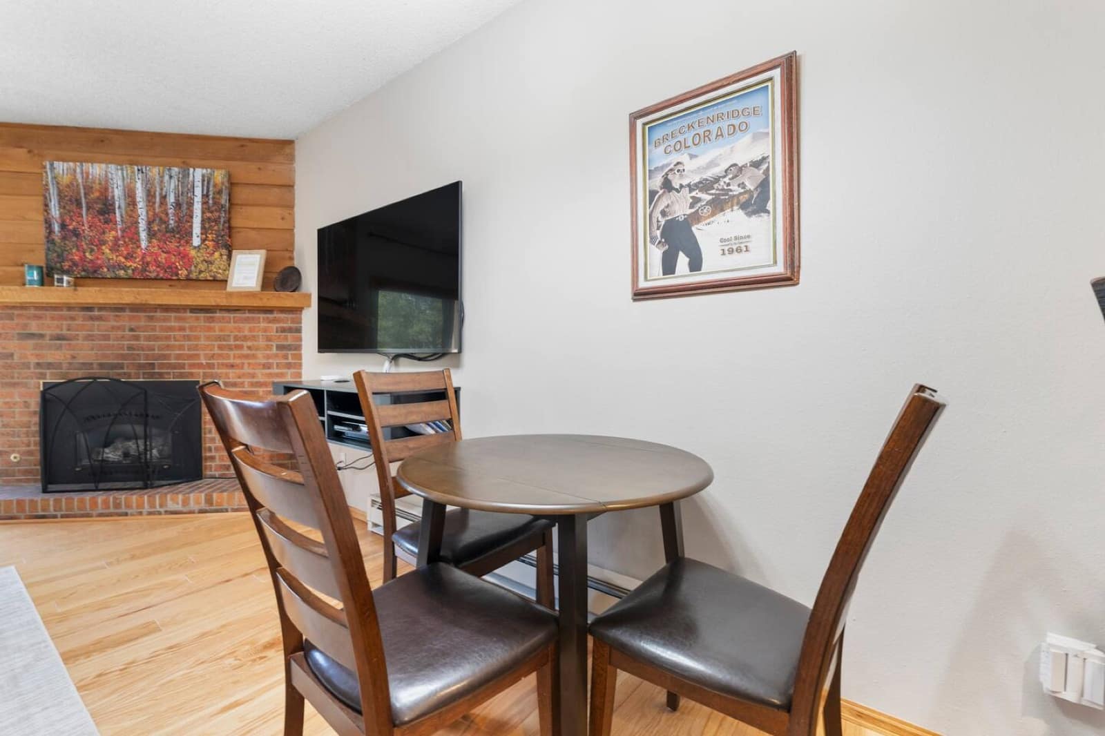 Dining table beside the brick fireplace and a vintage Breckenridge poster